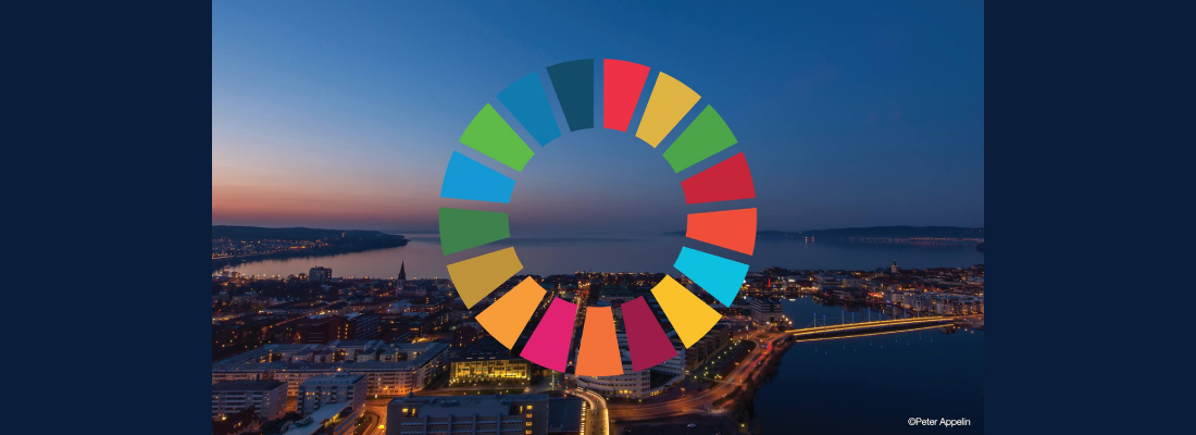 Drönarbild över centrala Jönköping på kvällen. Man skymtar solnedgången till vänster i bild. En glittrande stadssiluett syns i mörkret. Över bilden finns en ring bestående av kvadrater i olika färger.